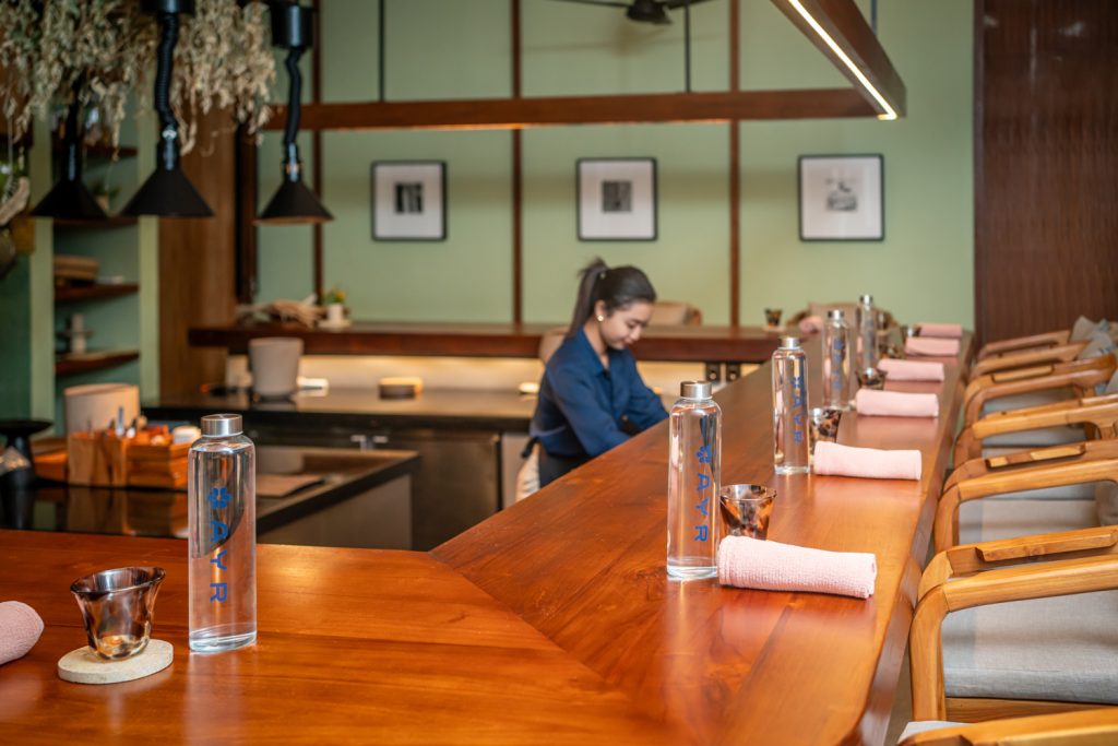 Waitress preparing fine-dining table setup in luxury restaurant with AYR Water bottled still and sparkling